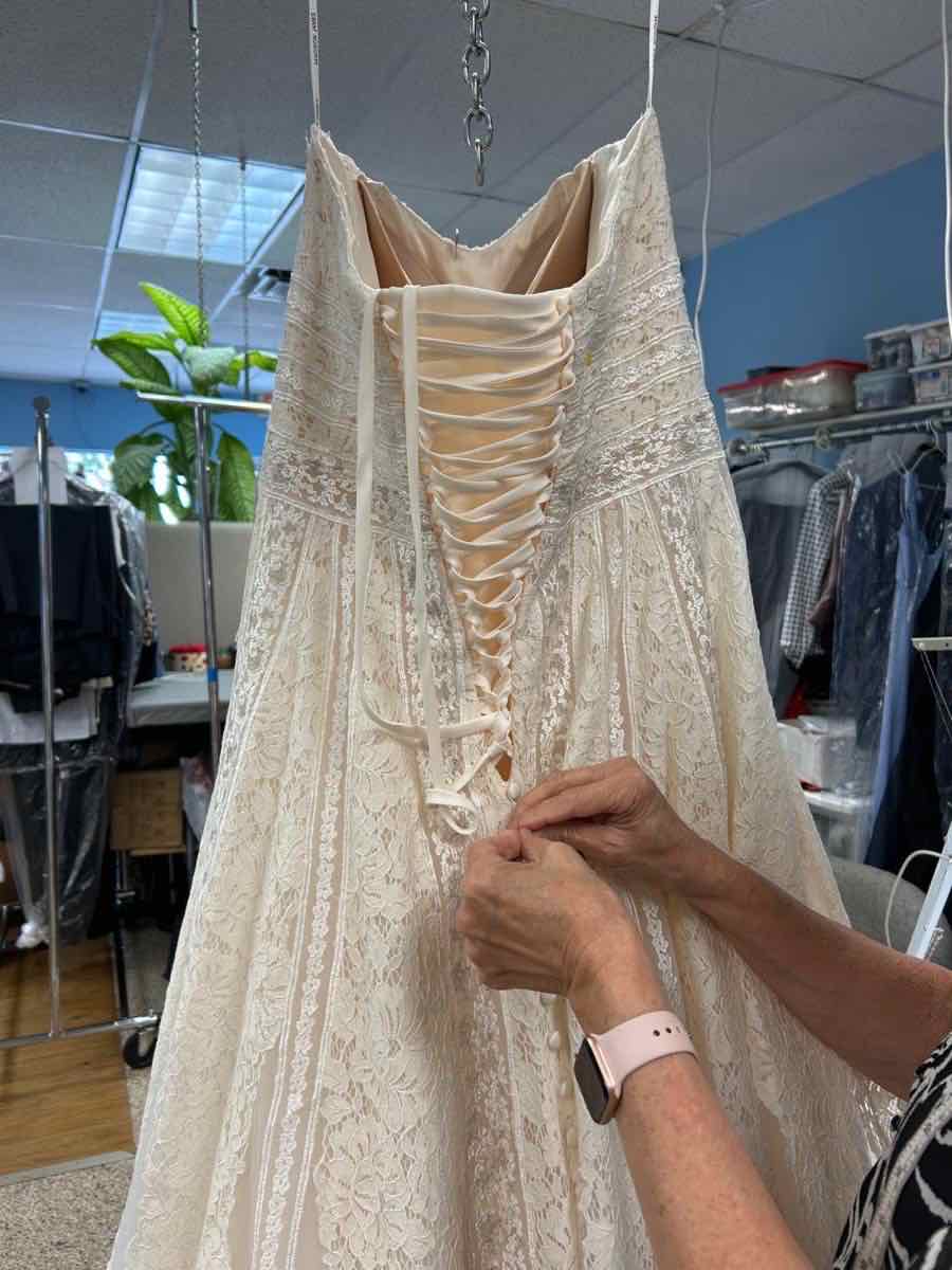 Hand-adjusting a corset lace-up back on a bridal gown